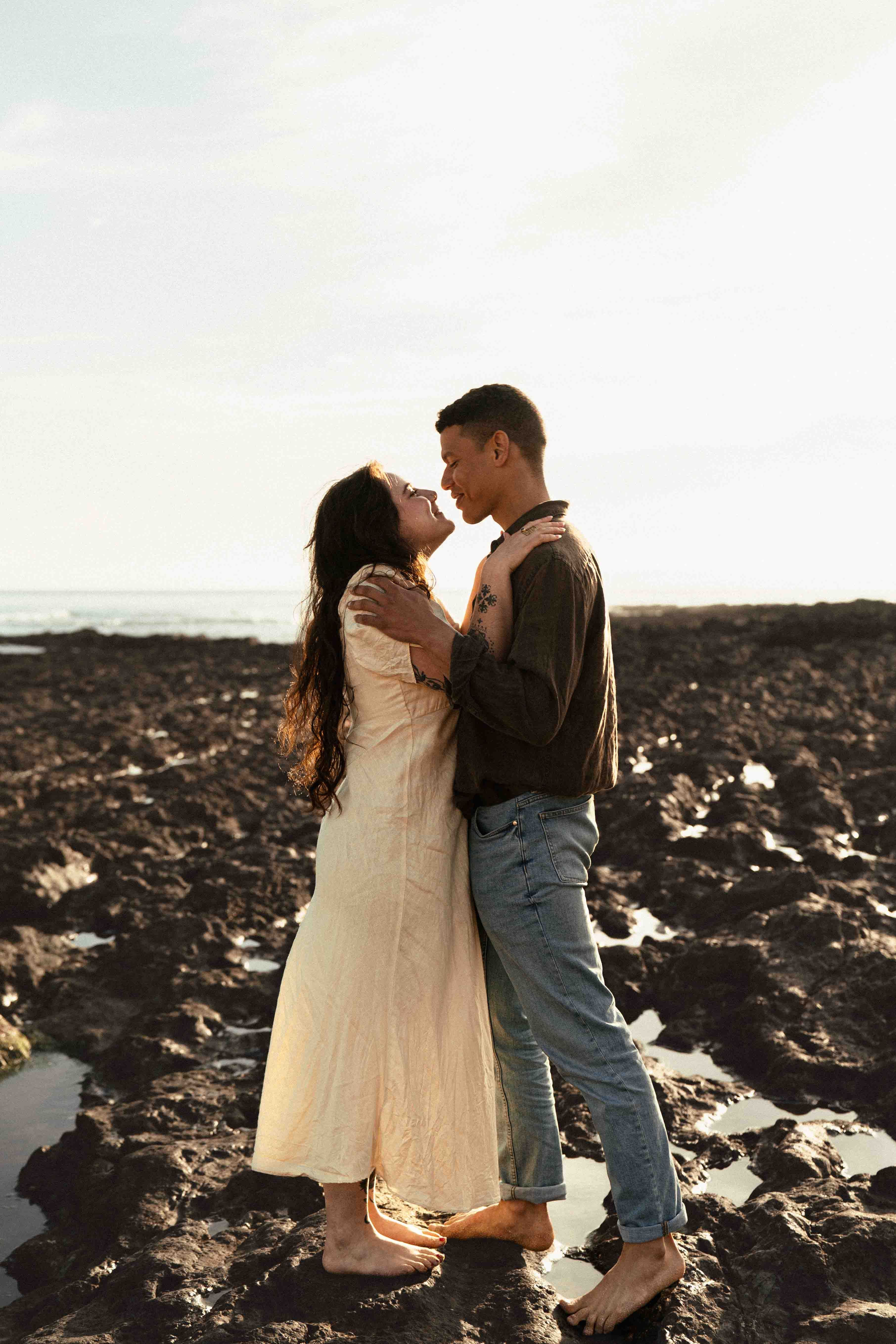 Couple enlacé au coucher du soleil sur les rochers